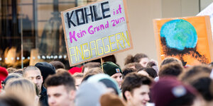 Jugendliche auf einer Demo, jemand hält ein Schild mit der Aufschrift "Kohle ist kein Grund zum Anbaggern"