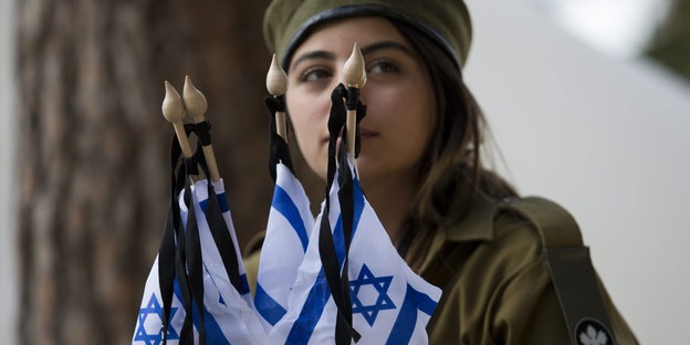 eine soldatin vor israelischen Flaggen