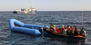 Ein Schiff der „Sea-Watch“ nähert sich einem Rettungsboot, um Menschen in Seenot zu retten