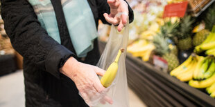 Jemand steckt eine Banane in eine Plastiktüte