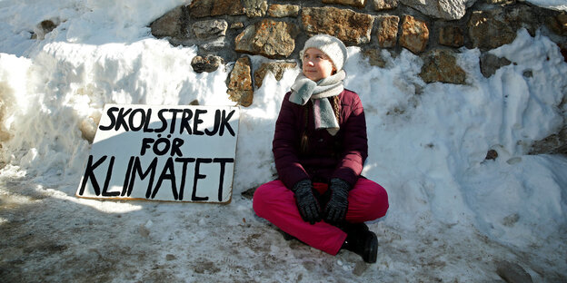 Die 16-jährige schwedische Klimaaktivistin Greta Thunberg sitzt im Schneidersitz im Schnee, neben ihr steht ein Protestschild mit der Aufschrift „Skolstrejk för Klimatet“