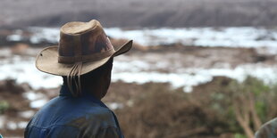 Ein Mann schaut auf eine Landschaft voller Schlamm