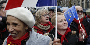 Menschen demonstrieren mit roten Schals und eingehüllt in EU-Flaggen