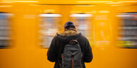 Ein Mann steht vor einer fahrenden U-Bahn