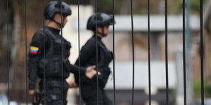 Zwei Sicherheitskräfte gehen hinter einem Zaun