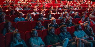 Menschen sitzen im Kinosaal und schauen auf die Leinwand