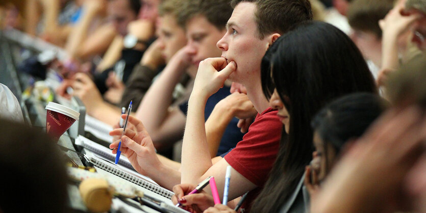 Studierende sitzen im Hörsaal und schreiben mit