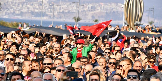 Menschen versammeln sich mit der türkischen Fahne am Meer