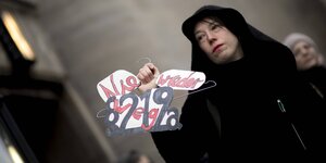 Eine Demonstrantin hält einen Drahtbügel in der Hand mit der Forderung: Nie wieder – weg mit 219a