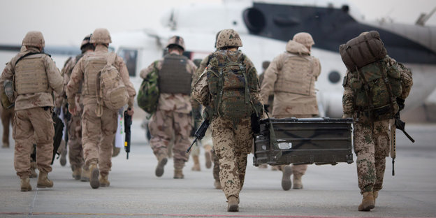 Einige Soldaten in Millitärkleidung laufen auf einen Hubschrauber zu