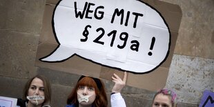 Junge Frauen, die ein Plakat mit der Aufschrft "Weg mit §219a" hochhalten