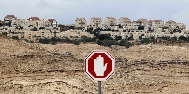 Ein Stoppschild in der West Bank, im Hintergrund mehrere Wohnhäuser