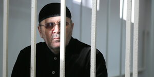 Ein Mann steht hinter Gitterstäben