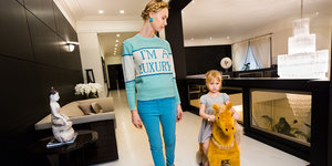 Eine Frau trägt einen Pulli mit der Aufschrift "I'm a Luxury", daneben ein grimmig dreinblickendes Mädchen auf einem Spielzeug-Pony