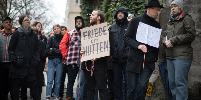 Eine Gruppe Menschen steht mit Protestschildern vor einem Haus