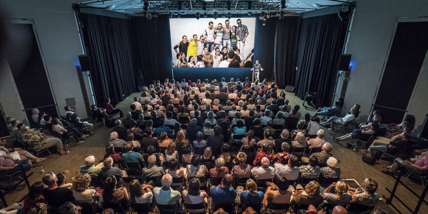 Saal von oben fotografiert mit vielen Sitzreihen voller Menschen