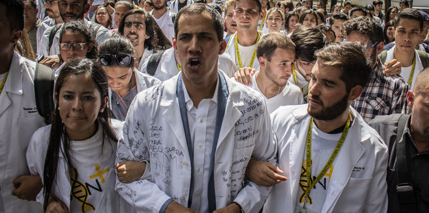 uan Guaido (Mitte), selbst ernannter Interimspräsidenten, marschiert in weißem Kittel mit Personal des Gesundheitswesens, Ärzten und Medizinstudenten gegen die Regierung von Präsident Maduro.
