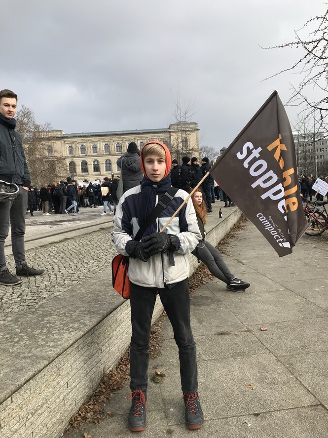 Eine Junge mit einer Fahne auf der "Kohle stoppen" steht.