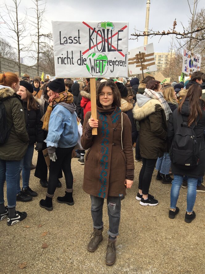 eine junge Frau hält ein Plakat auf dem steht: "Lasst Kohle nicht die Welt regieren"