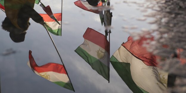 iranische Flaggen spiegeln sich in Regenpfützen und stehen somit auf dem Kopf