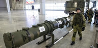 Ein Soldat neben einer meterlangen Rakete in einer Halle