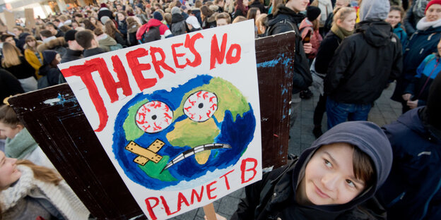 Junge auf einer Demo hält ein Schild hoch. Darauf steht: There's No Planet B.