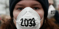 Demonstrantin mit Atemmaske, auf der 2038 steht