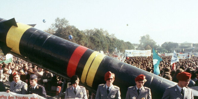 Menschen in Uniform vor einer Raketenattrappe