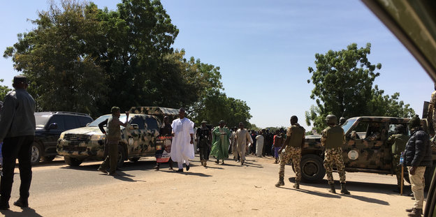 Soldaten sichern eine Sandstraße ab, die ein Präsidentschaftskandidat entlanggeht