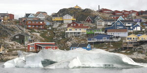 Bunte Häuser stehen auf einem Hügel vor Wasser und Eis.
