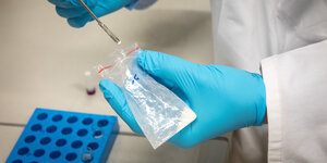 Chemiker mit blauen Handschuhen mit Pipette und Reagenzglas
