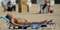 Ältere Frau im Bikini auf einer Strandliege