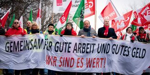 Gruppe von Menschen protestieren. Auf dem Banner, den sie tragen steht "gemeinsam für gute Arbeit und gutes Geld".