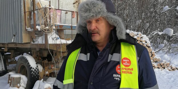 Älterer Mann mit geler Signalweste im Schnee