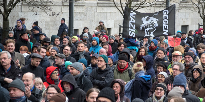 in einer Menschenmenge wird ein Transparent hochgehalten, auf dem steht: „Gegen Nazis“