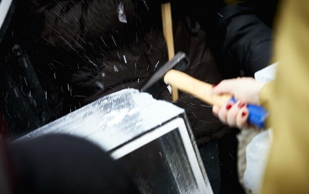 Eine Person schlägt mit einem Hammer auf einen Eisblock