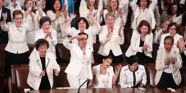 Mehrere Frauen, die in weiß gekleidet sind, klatschen.