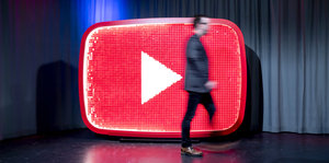 Youtube-Logo als Bühnenskulptur, ein Mann geht schnell daran vorbei