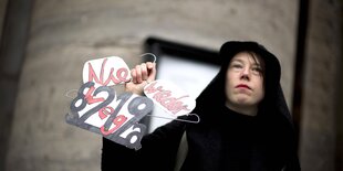 Frau mit Plakat und kleiderbuegel in der hand