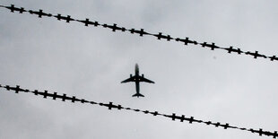 Vor einem Stacheldraht ist ein Flugzeug zu sehen