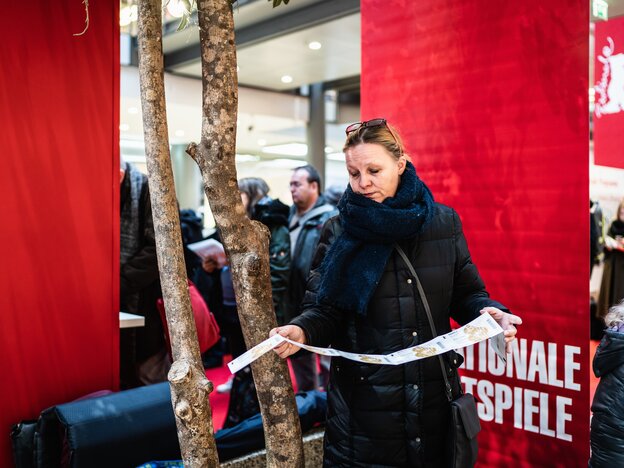Eine Frau steht und hält Kino-Karten, sie sieht etwas enttäuscht aus Eine Frau steht und hält Kino-Karten, sie sieht etwas enttäuscht aus