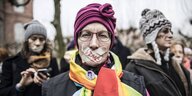 Eine Frau auf Demo mit zugeklebtem Mund, darauf steht 219a