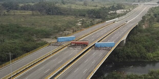 Die Fahrbahn einer mehrspurigen Autobahn ist auf der Brücke über einen Fluss durch einen Tanklaster und zwei Container versperrt.