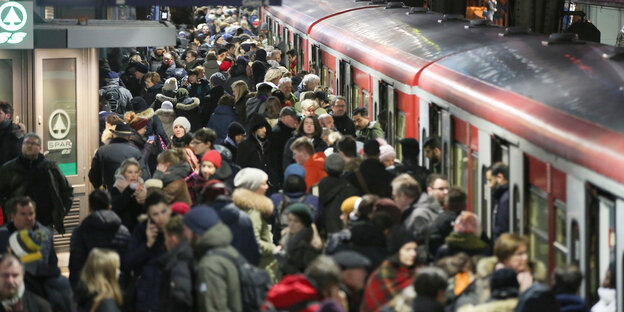 Reisende stehen am Hamburger Hauptbahnhof an einem S-Bahn-Gleis.