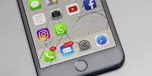 Ein zerschlagenes Handy-Display zeigt das App-Symbol von Facebook und anderen sozialen Netzwerken