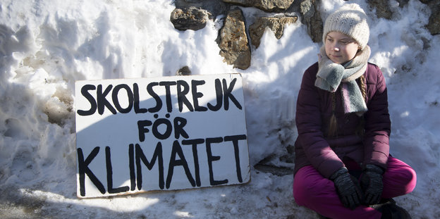 mädchen mit Mütze und Schild "Schulstreik fürs Klima" im Schnee