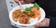 ein Pappteller mit Sojafleisch, Kimchi, Daikon, Spinat und Reis