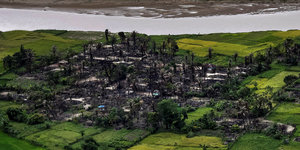 In Myanmar ist ein niederbegranntes Dorf von grünen Feldern umgeben