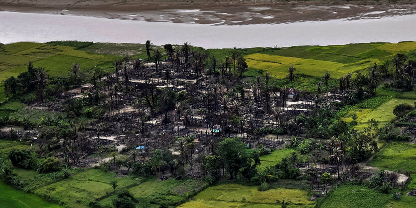 In Myanmar ist ein niederbegranntes Dorf von grünen Feldern umgeben