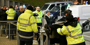 Mitarbeiter eines Sicherheitsunternehmens kontrollieren Stadionbesucher vor einem Fußballspiel.